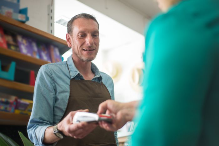 Shopkeeper processing a card payment for a customer