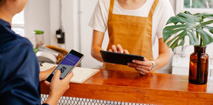 Store team member scanning a customer's loyalty app while chatting with her