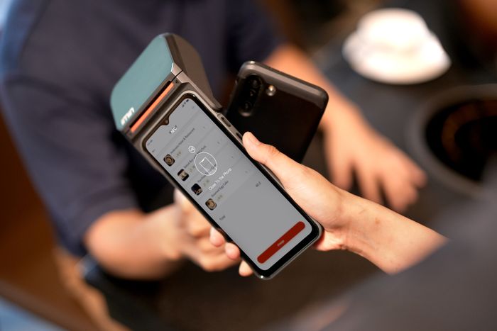 Till scanning a cardholder's digital wallet on her phone screen